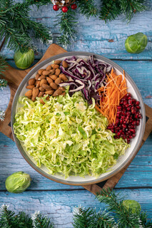 <p>In a medium bowl toss together the sprouts, carrot, cabbage, and half of the pomegranates.</p><p>Add the dressing to the bowl but leave some for the final serving.</p><p>Tip the mixture on a serving dish, top with remaining pomegranates, the spicy almonds and generous drizzle of the dressing.</p>