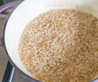 <p>Heat up the olive oil in a pan and add in the diced onion.</p><p>Fry for around 2 minutes, then add in the minced garlic.</p><p>Fry for another minute or so before adding the rice; fry it off for a few seconds until every rice grain is coated.</p><p>Now add the first cup of your hot stock</p>